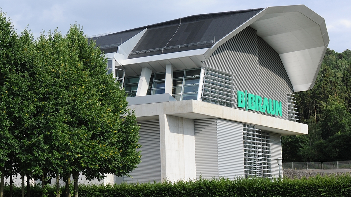 Bâtiment du centre de visite B. Braun avec un grand logo B. Braun, rayonnant d’hospitalité et d’ouverture à tous ceux qui s’approchent. 