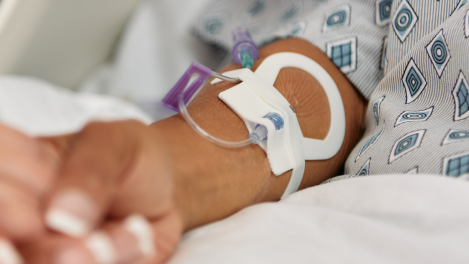 Patient with a Introcan Safety 2 peripheral IV catheter secured by All-In-One Clik-FIX securement device holding a loved one's hand